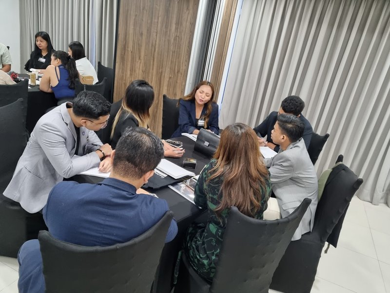 A small group of participants practices a coaching exercise together around a table.