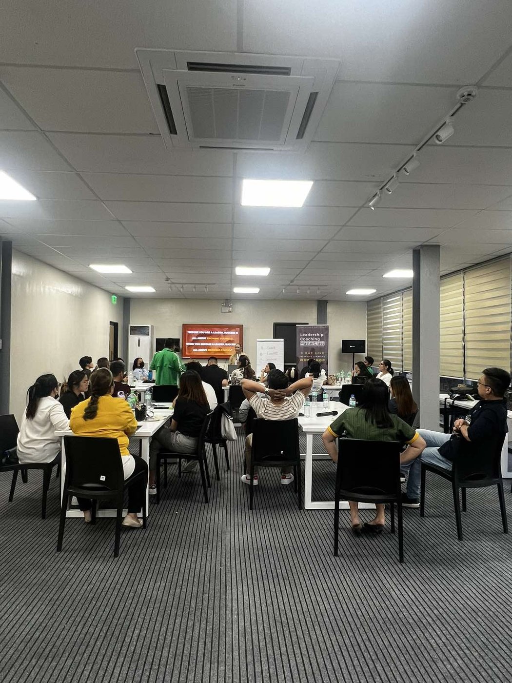 A full room of participants faces the front during a packed Leadership Coaching MasterClass session.